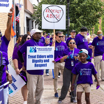 adult leads a group of participants holding signs during an elder abuse awareness march in Brockton.