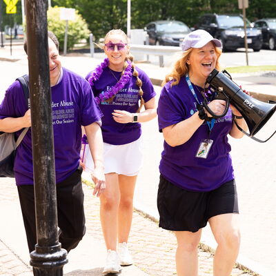 March participants walk together in Brockton holding signs during an elder abuse awareness event.